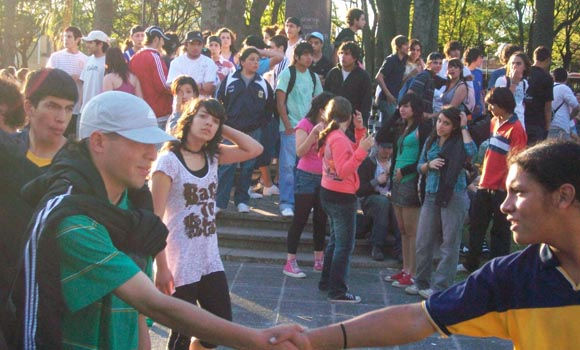 El saludo de dos jóvenes en medio de una plaza invadida por los estudiantes.