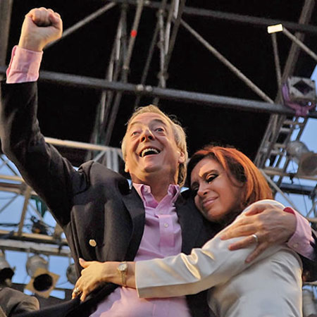 La euforia habitual de Kirchner, en un acto, acompañado por un gesto de ternura de Cristina.