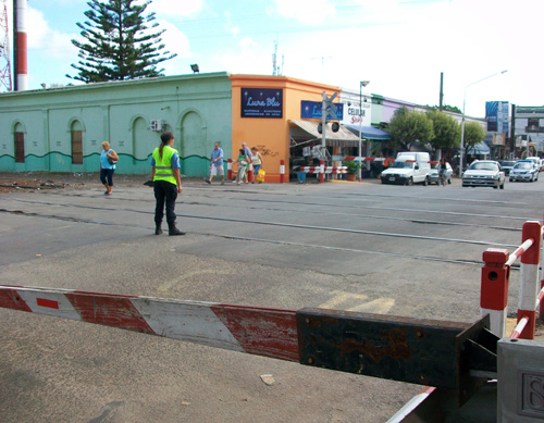 Un agente municipal sobre las vías de Tapia de Cruz, entre las barreras bajas y sin ningún tren a la vista.